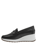 Mocasín de mujer elegante en cuero negro con adorno metálico discreto en el talón.