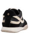 Zapatilla de mujer negra con detalles en charol, perfecta para un look moderno y cómodo.